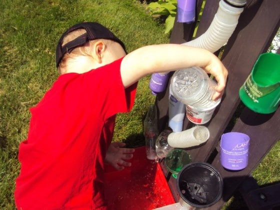 pouring water into containers in a homemade water activity for the backyard