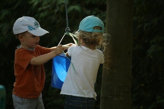 preschool boy and girl playing with bucket and rope pulley system