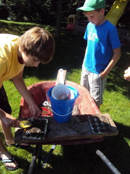 boys playing in wheelbarrow mud kitchen