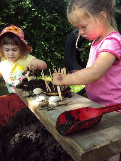 kids using a wheelbarrow as a mud patch