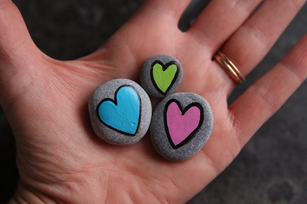 3 painted heart worry stones in palm of hand