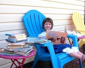 young girl reading and surrounded by books