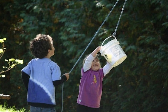 2 preschoolers having fun with the bucket and rope contraption