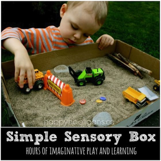 Construction sensory bin - cardboard box, sand and toy trucks