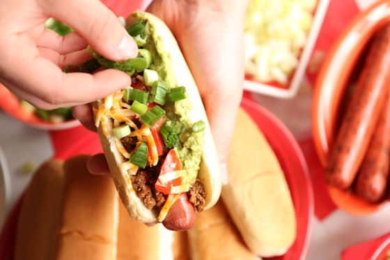 Adding green onions to a taco dog