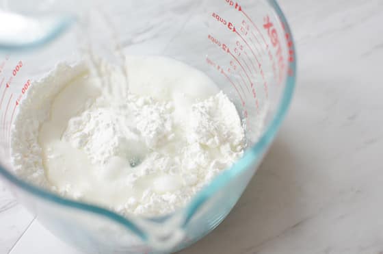 pouring water into cornstarch in measuring cup