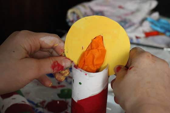 child attaching flame to paper towel roll candle