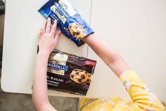 child putting hand inside bag of chocolate chips