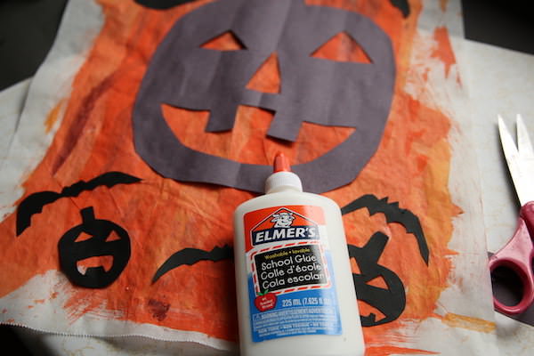 glue bottle, pumpkin and bat shapes on orange painted parchment paper