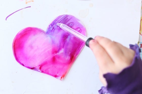 child dripping alcohol onto plastic heart coloured with Sharpies