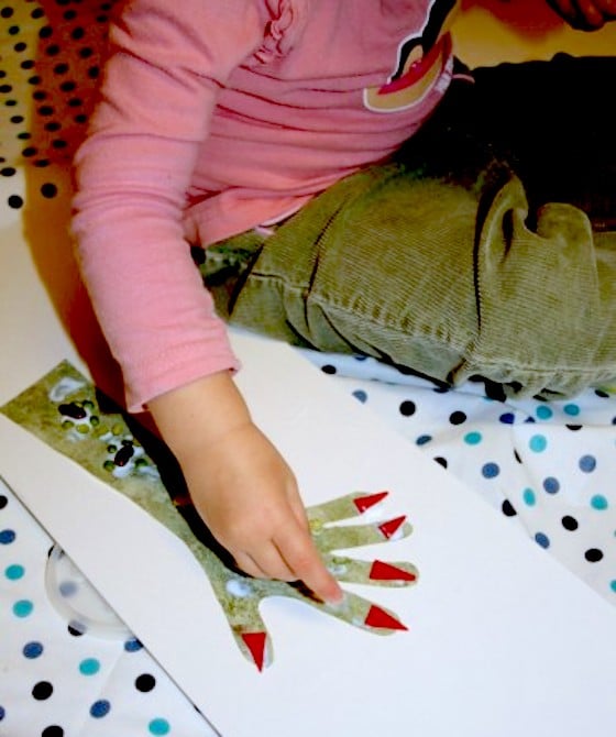 child gluing lentil warts on monster hand