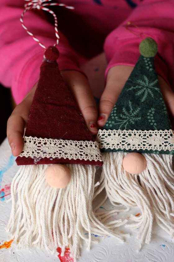 Child holding 2 homemade gnome ornaments