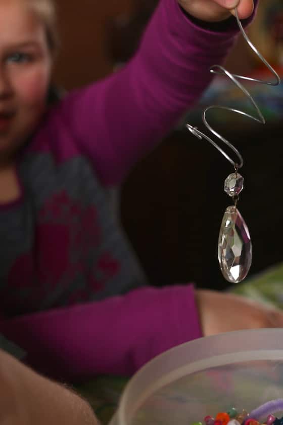 child holding chandelier bauble threaded onto wire