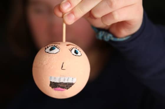 child-holding-self-portrait-ornament-on-wooden-skewer