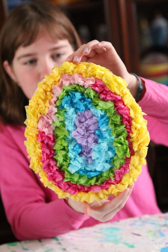 Child holding up tissue paper egg craft