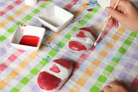 child painting Canada Flag on Beach Rocks