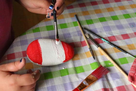 Child painting Canada Flag on Beach Stone