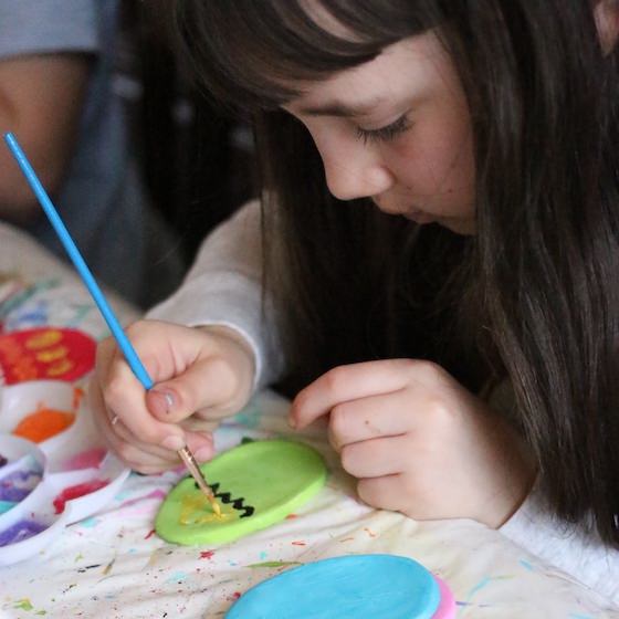 child painting chick on white clay egg