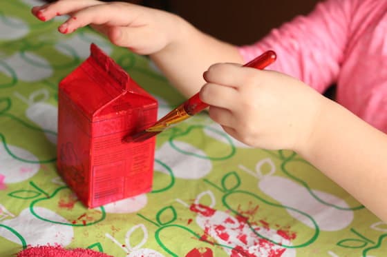 child painting milk carton red