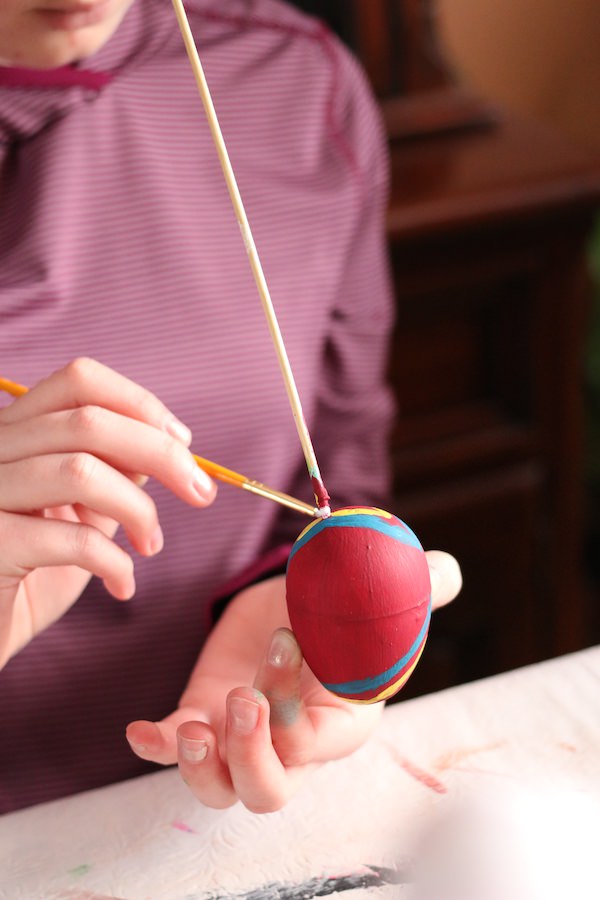 child painting plastic easter egg