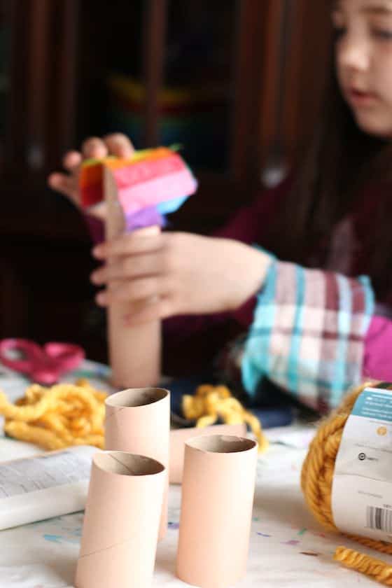 Child painting toilet rolls flesh colour