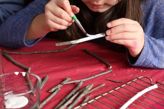 child painting twigs white