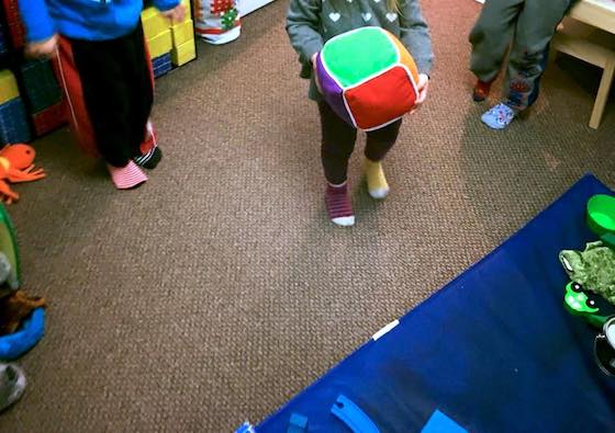 Child rolling large coloured dice