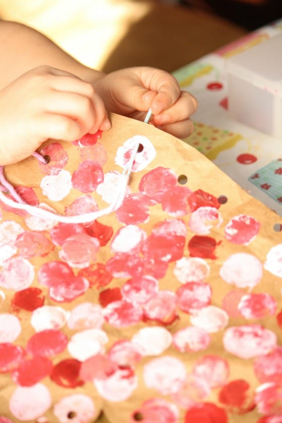 child sewing edges of a paper bag