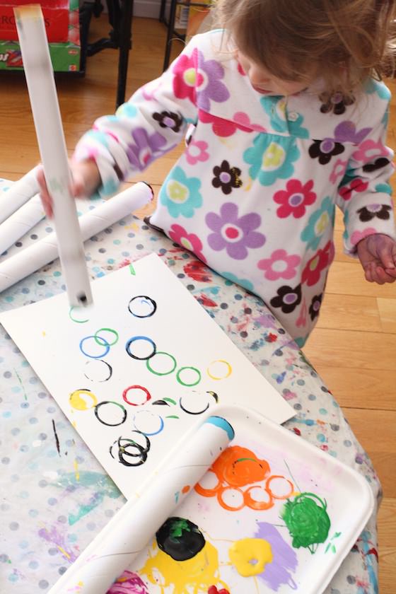 toddler making olympic rings craft with cardboard roll and paint