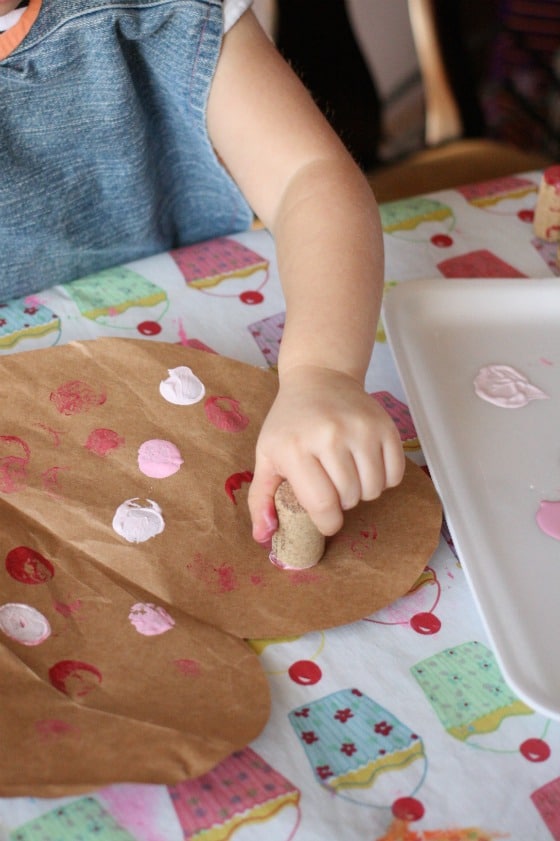 child stamping valentines hearts with corks