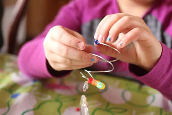 child threading beads onto florist wire spiral