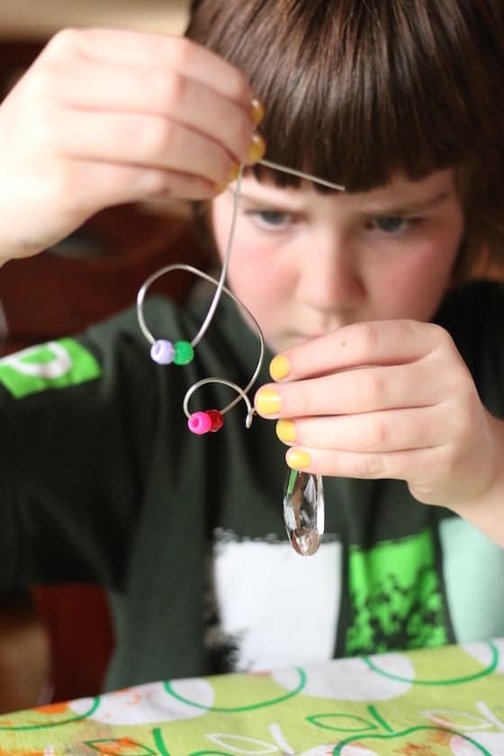 child threading pony beads onto thin guaged wire