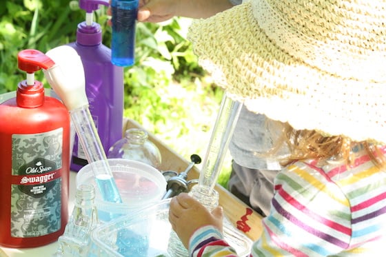 Child using turkey baster to transer water into glass bottle