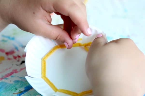 child weaving on paper plate