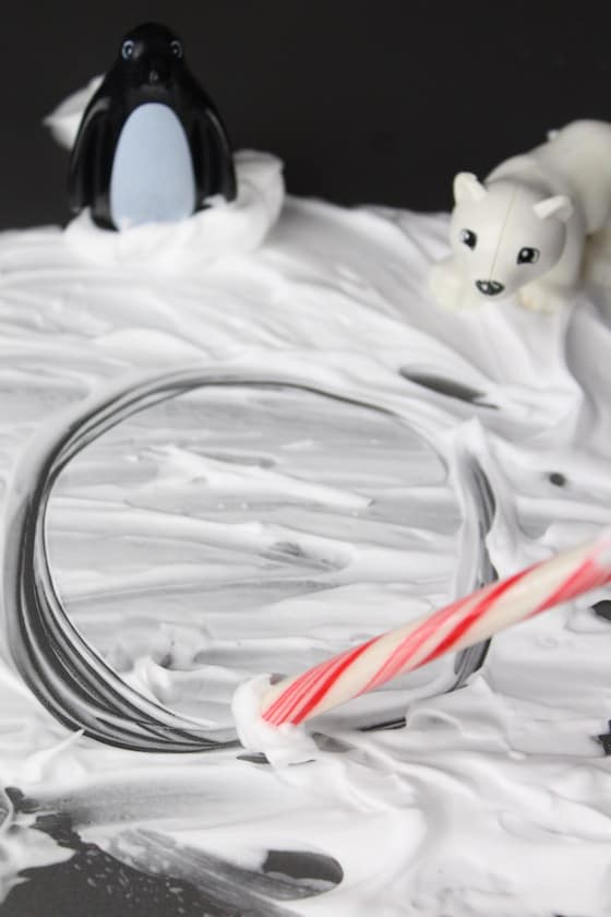 Child writing in shaving cream with candy cane