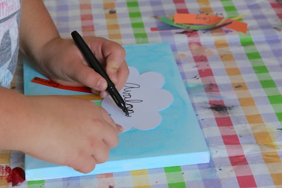 Child writing name on paper cloud