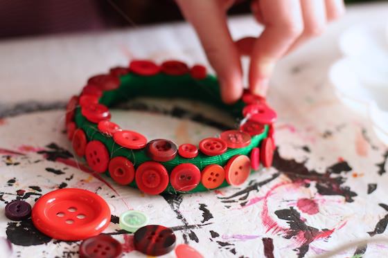 closeup kid gluing red buttons on green ribbon mason lid