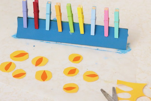 coloured clothespins on blue menorah paper flames on table