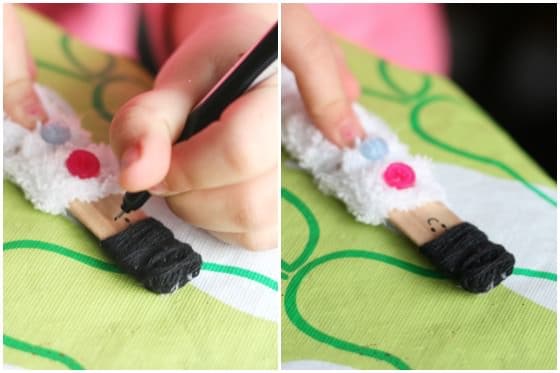 Decorating a craft stick doll with buttons and yarn