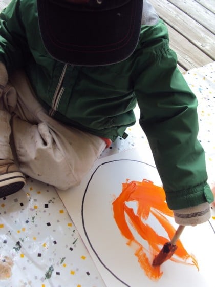 toddler painting a jack o lantern on white paper