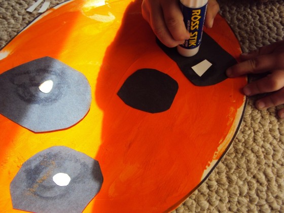 Toddler gluing paper jack o lantern