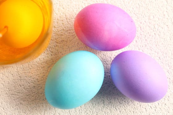 3 coloured eggs beside egg in yellow food colouring 