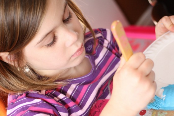 girl painting paper plate blue