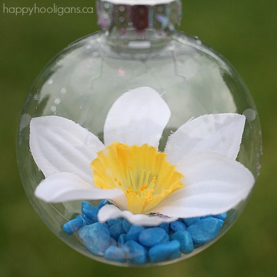 clear plastic ornament with blue aquarium stones and artificial daffodil inside