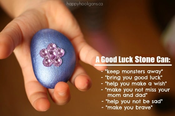 Child's hand holding purple good luck stone with pink flower