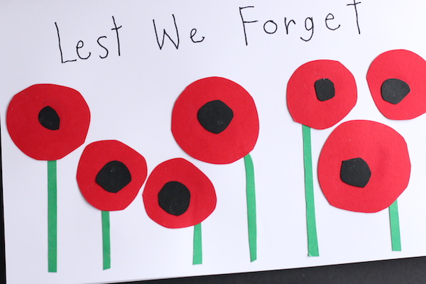 white yardstick folded horizontally 7 circle poppies with words lest we forget