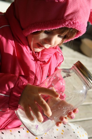 toddler shaking jar with glitter in it