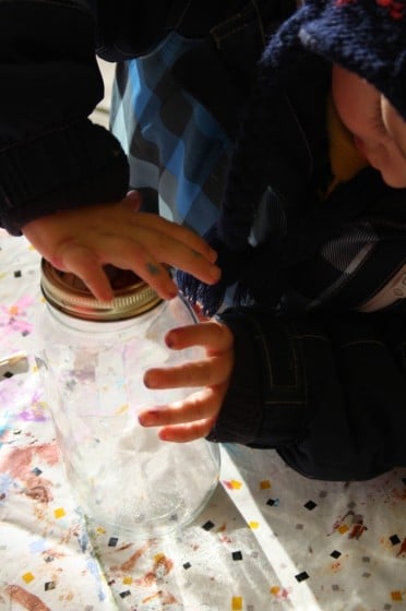 child putting lid on jar