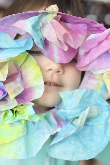 child peeking through easter wreath made with dyed coffee filters