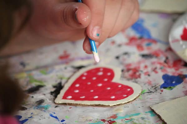 Child dotting paint with handle end of paintbrush